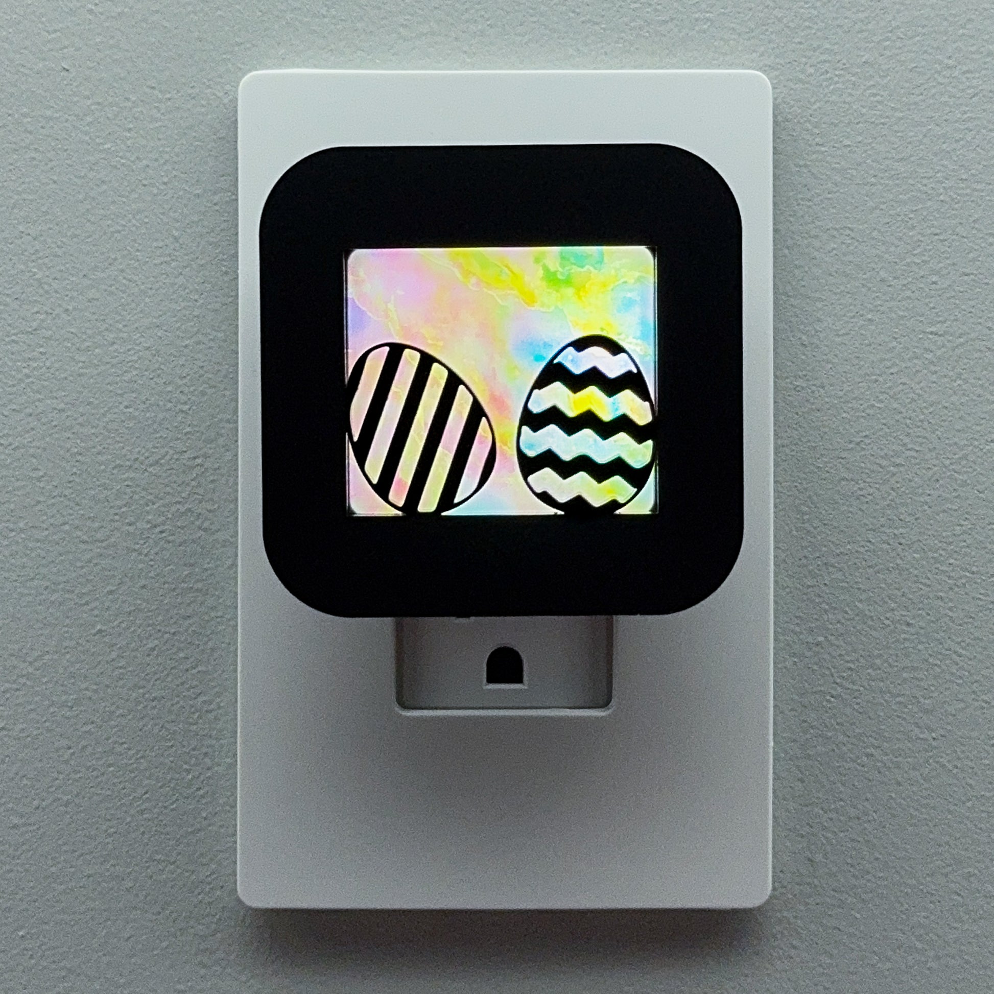Decorative night light with Easter egg design on a gray wall